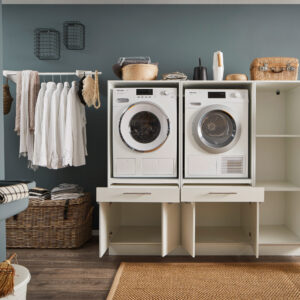 Weiße Waschkombination mit geöffneten Schränken und Auszügen, zwei integrierten Geräten und großzügigem Stauraum in modernem Waschraum.