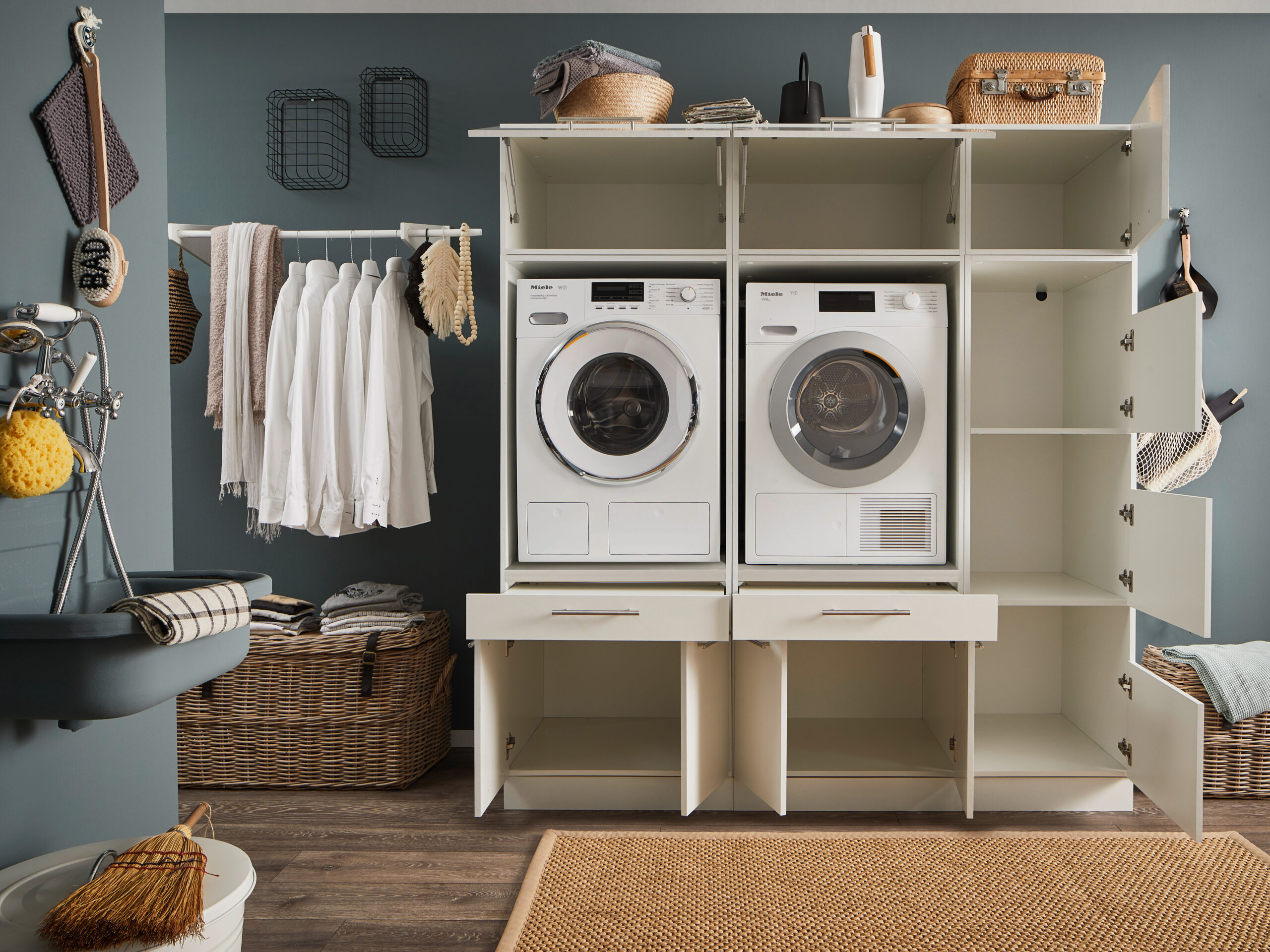 Laundreezy LDSK11W Milieu offen_91-220-17_70-200-17+37-202-17+70-201-17+37-201-17 Geöffnete weiße Waschkombination mit Waschmaschine, Trockner und vielen offenen Fächern in einem Hauswirtschaftsraum.