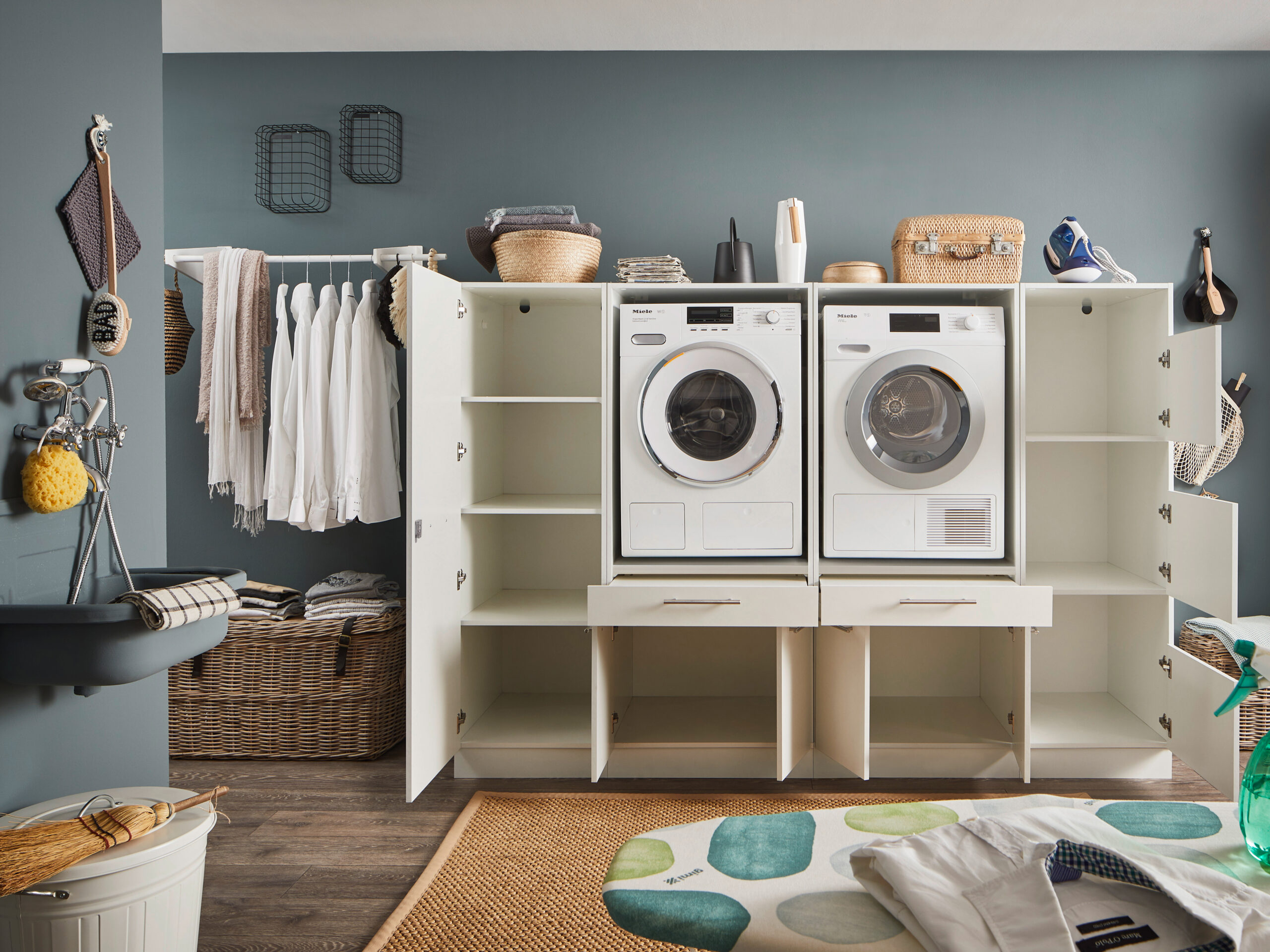 Laundreezy LDSK14W Milieu offen_91-224-17_70-202-17+70-200-17+70-201-17 Geöffnete weiße Waschmaschinen Schranklösung mit sichtbaren Fächern und integriertem Waschmaschinen Duo in modernem Waschraum.