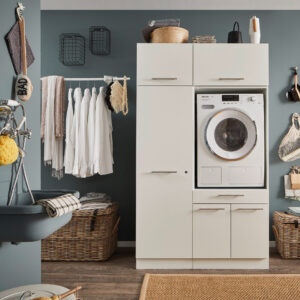Waschbereich mit Schrankelementen Ein Waschraum mit eingebauter Waschmaschine in einem weißen Möbelmodul, Kleiderstange mit weißen Hemden, Körben und einem Wandwaschtrog.